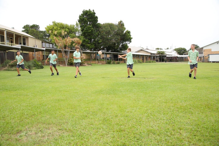 A group of students playing touch football on the oval during break time.
