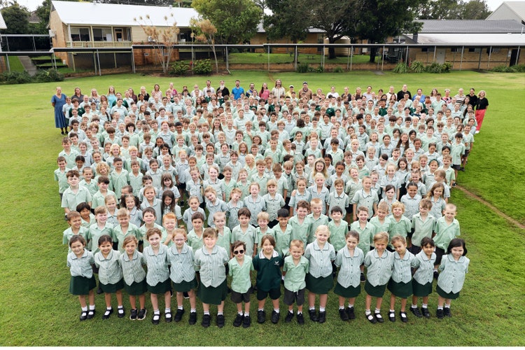 A whole school photo including all staff and students standing on the oval.