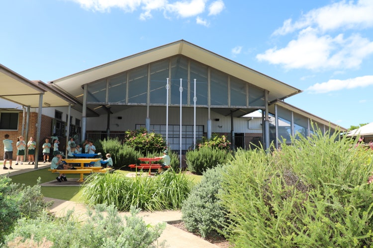 A photo of our quiet area space with a path leading up to the canteen. Students are sitting on the colourful tables and walking up to the canteen to purchase food at break time.