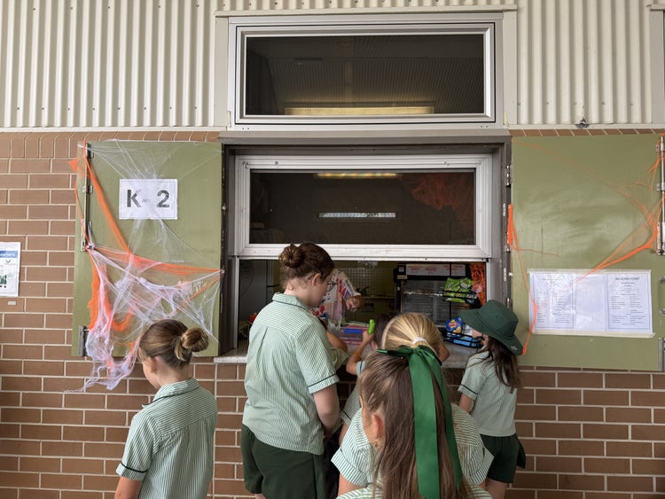 Students lining up in front of the canteen at break time. There is a halloween display on the canteen as this photo was taken at the end of October.
