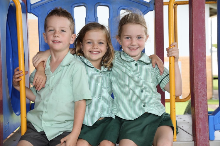 Three friends sitting together and enjoying themselves on the play equipment during break time.