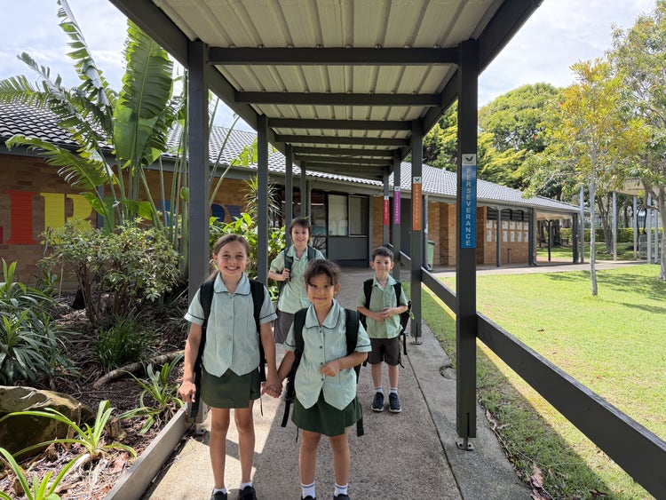 Students walking along the footpath past the front entrance and library, heading to the COLA area to start the day.
