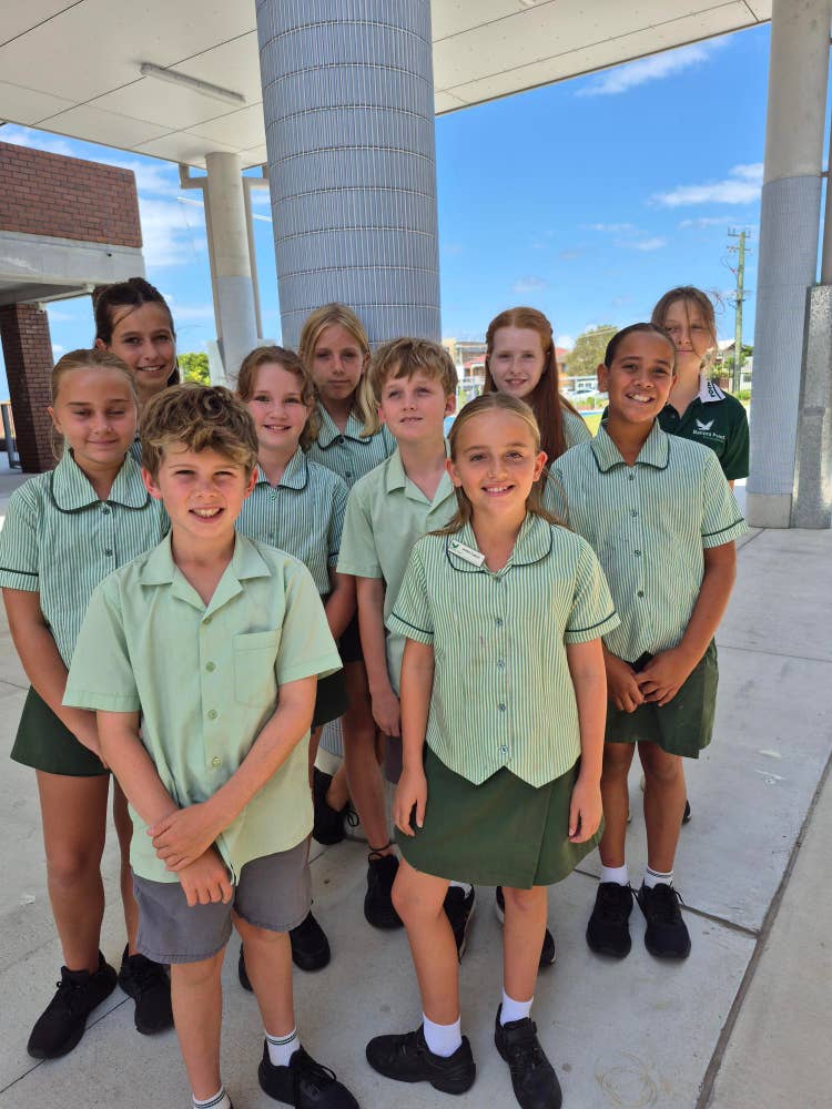 Our debating team standing outside a school smiling happily at the camera before their competition.