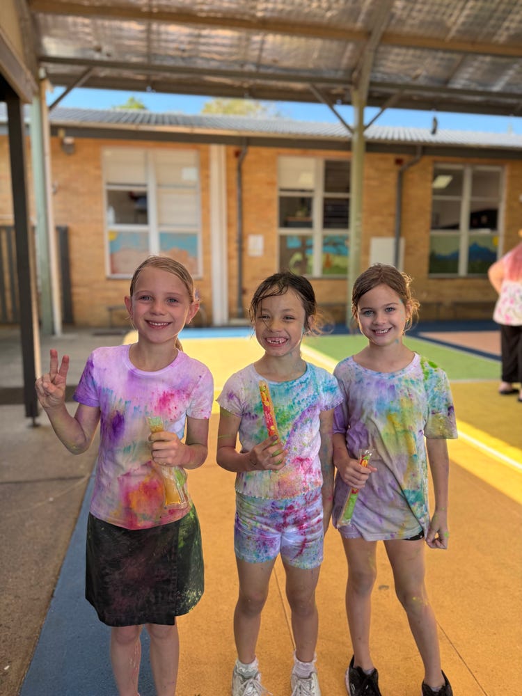 Three students smiling happily after doing the colour fun run.